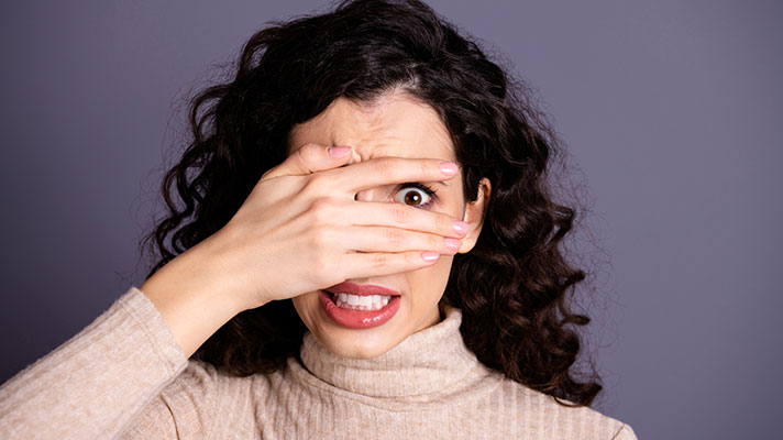 Scared woman covering her eyes.