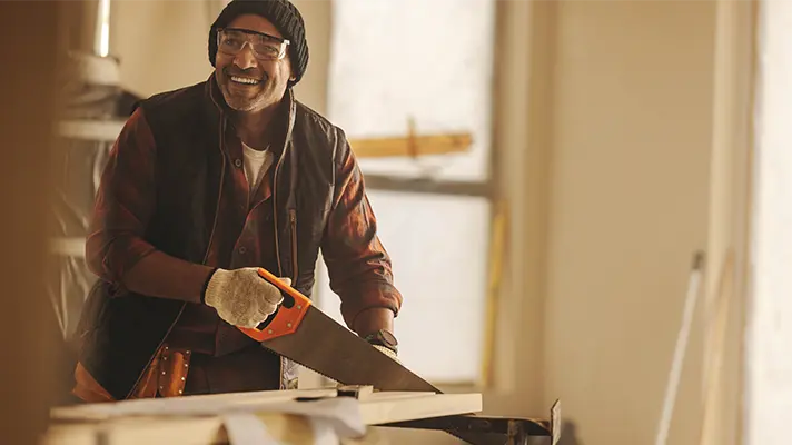 contractor using a hand saw and smiling