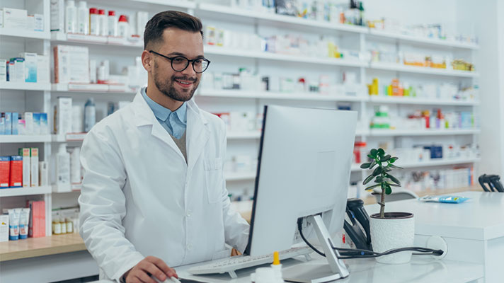 male pharmacy worker smiling at computer
