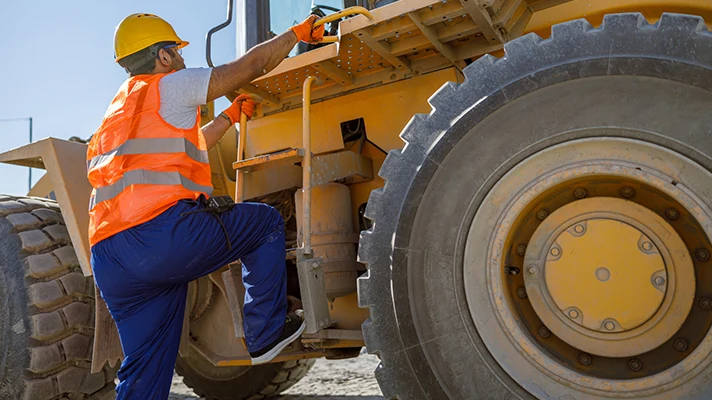 worker climbing into heavy equipment using the three points of contact rule