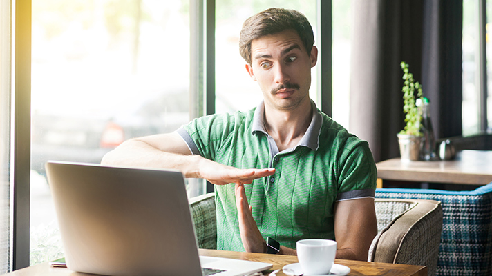 young man giving a time out signal to his laptop computer