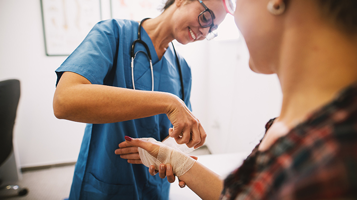 injured worker having hand taped by doctor