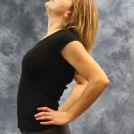 person with hands on lower back and arching back to look upward