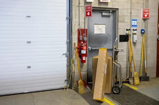 an emergency exit and fire extinguisher blocked by boxes