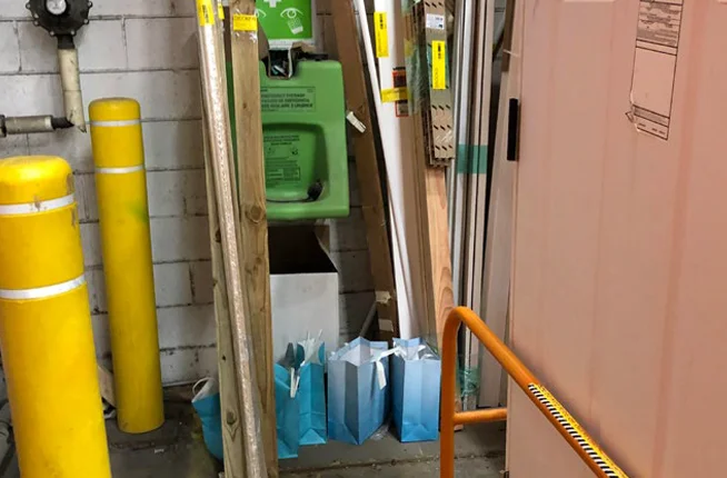 an eyewash station blocked by stacked lumber