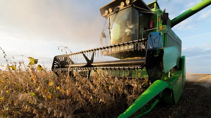 person driving a combine machine in a field