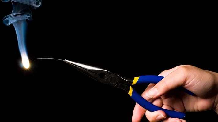 magnesium set afire with person holding pliers pinching magnesium wire