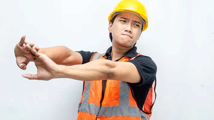 construction worker with hard hat and safety vest stretching his arms