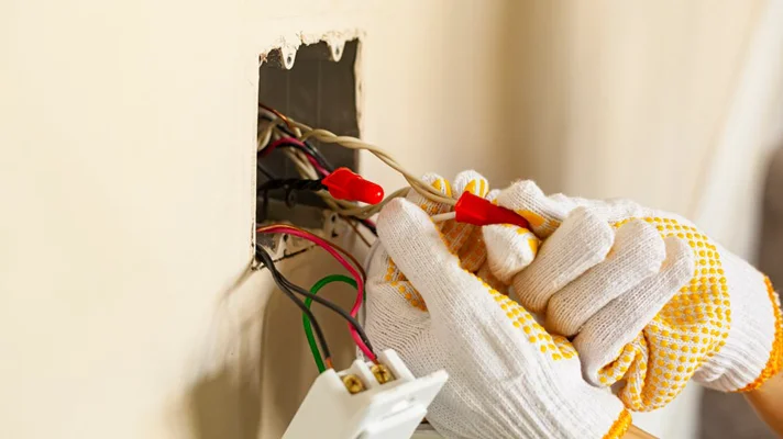 person with gloves working with electrical wires