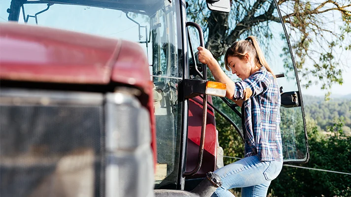 woman climbing up the side of a tractor