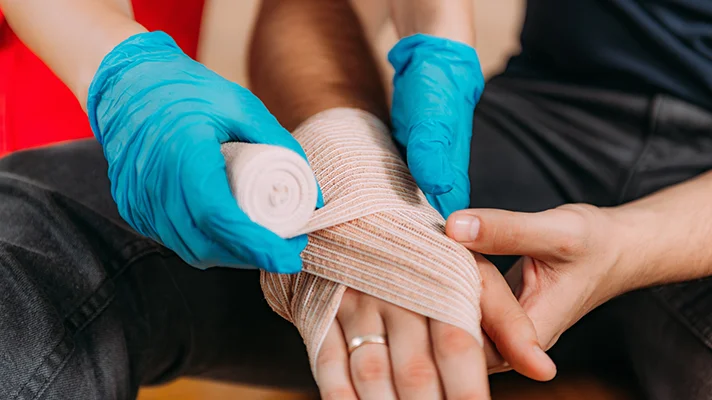 someone wrapping a man's hand in a bandage