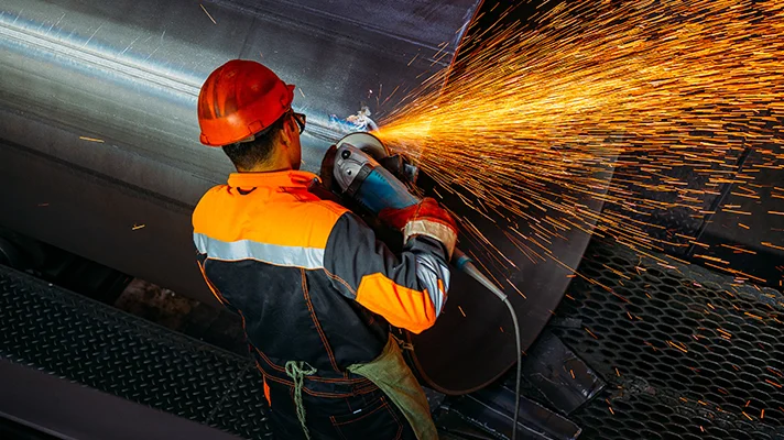 worker grinding metal with sparks flying
