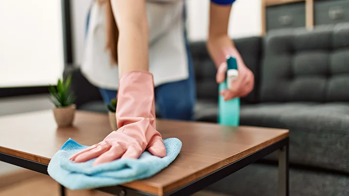 housekeeper bending to clean a coffee table