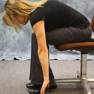 person sitting and bending at the waist to touch the floor