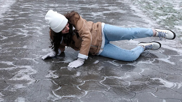 woman laying on icy sidewalk after falling