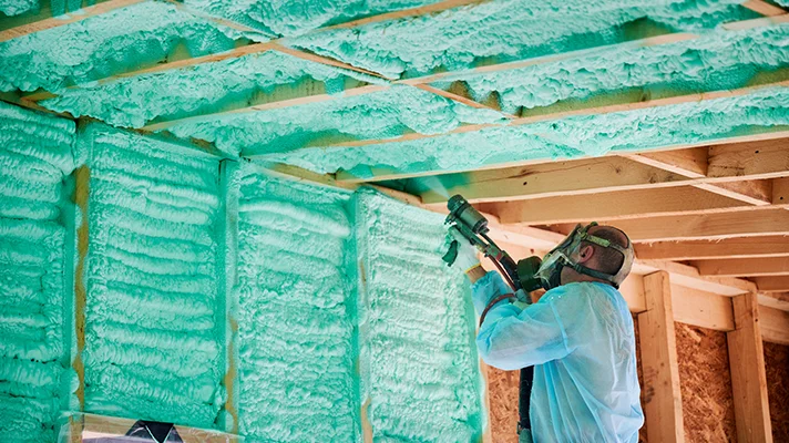 installer spraying foam into a stick framed structure