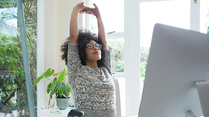 person at a desk stetching her arms over her head