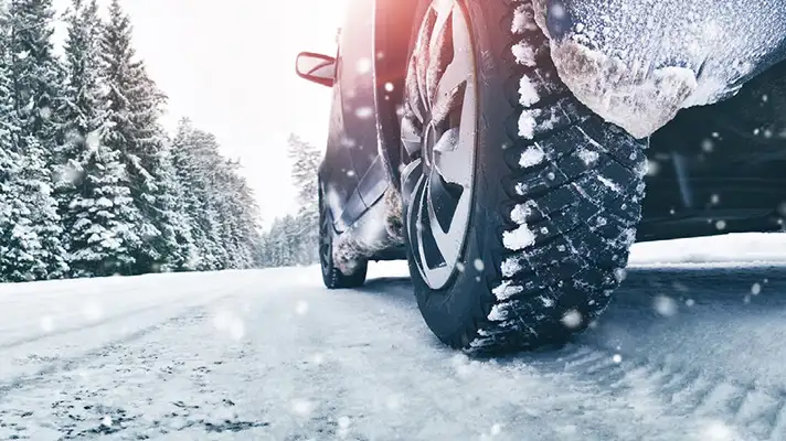 close up of a rear tire on a vehicle driving in snow